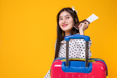 夏日休闲装的女游客。亚洲微笑女子。以黄色为背景出国旅行的乘客。一个亚洲女人要去度暑假。旅行有趣的旅行
