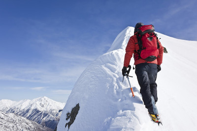 红衣登山运动员攀登白雪皑皑的山峰