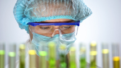女实验室工作人员戴着防护面具和护目镜研究样本
