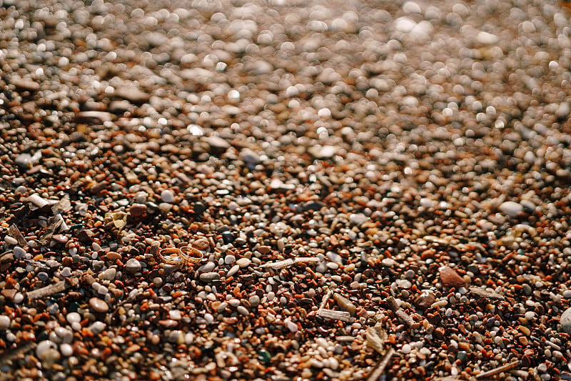 Gold wedding rings on a pebble beach.