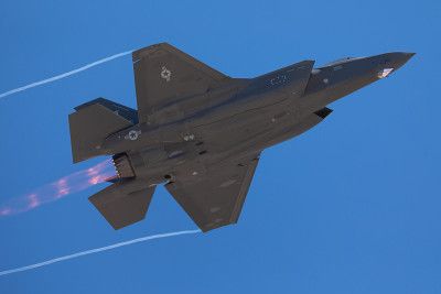 F-35闪电II的底部视图与加力燃烧器和凝结尾在机翼的尖端