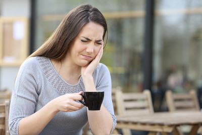 在露台上拿着咖啡杯的女人牙痛