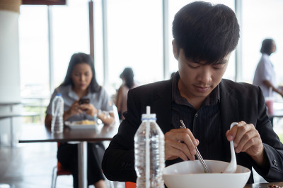 亚洲人在美食广场吃午餐。与社会的距离
