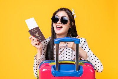 夏日休闲装的女游客。亚洲微笑女子。以黄色为背景出国旅行的乘客。一个亚洲女人要去度暑假。旅行有趣的旅行