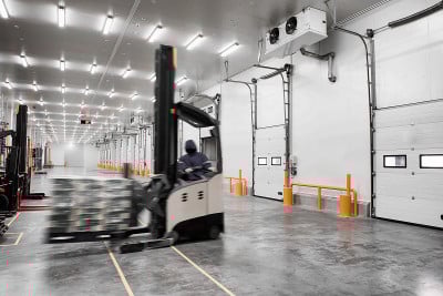 工人站立式堆垛车，用于提升和移动冷藏室或冷冻室的即食食品库存。