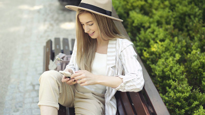 年轻的金发女人在城市公园打电话。
