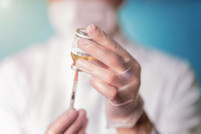 身穿白色医用围裙和口罩的科学家展示了新型冠状病毒疫苗。疫苗接种对冠状病毒。COVID-19疾病。