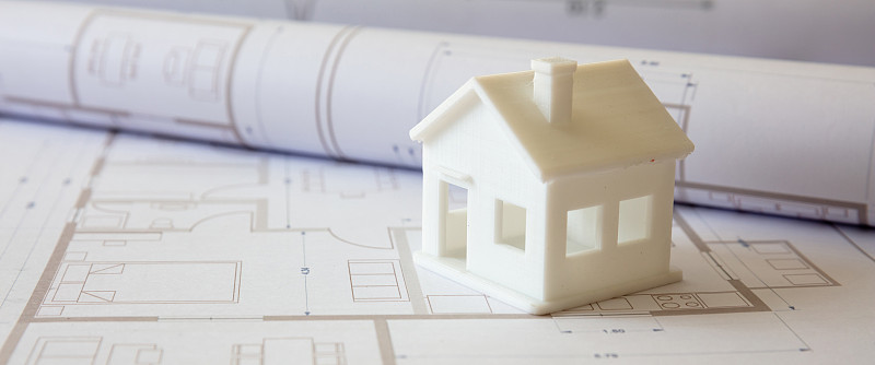 建筑的概念。办公桌上有住宅建筑图纸和建筑房屋模型