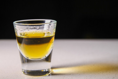 一个烈酒小酒杯，投射出金色的影子。