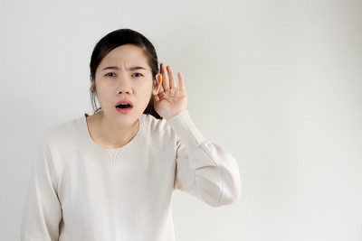 亚洲美丽的听力有问题的聋女用手杯耳听新闻、信息和交流。