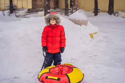 孩子在雪地上玩得很开心。男孩骑着一根管子。孩子们的冬季乐趣