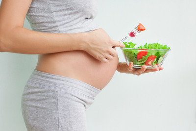 健康的营养和怀孕。孕妇的肚子和蔬菜沙拉。孕期营养。素食主义和怀孕。孕期维生素，孕期饮食