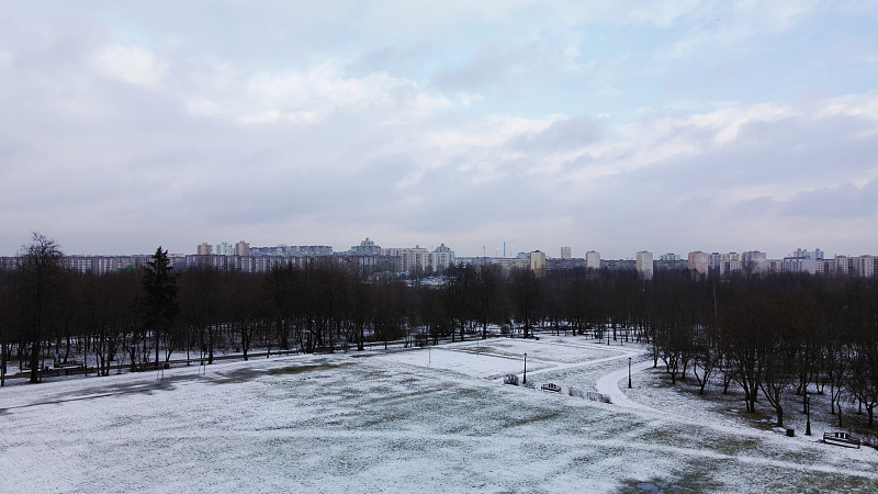 在冰雪覆盖的城市公园的运动场上空飞翔。航空摄影。