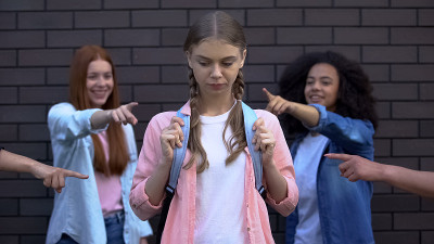 同学们笑着用手指指着拿书包的女学生，恃强凌弱