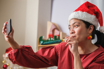 亚洲妇女戴圣诞帽视频电话聚会与朋友与移动电话桌上在家里