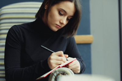 女人做笔记并四处寻找想法。冬天穿着衣服的时尚微笑女人的肖像女性冬季风格。——图片