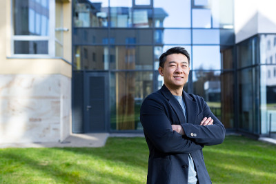 肖像英俊的亚洲人大学学院教师，商人，科学家或教育家。站在现代办公中心或校园背景，双臂交叉站在户外，对
