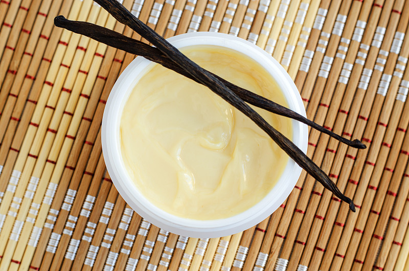 黄色香草面膜(香蕉霜，乳木果面膜，身体黄油)在小的白色罐子。天然护肤护发理念。俯视图，复制空间。