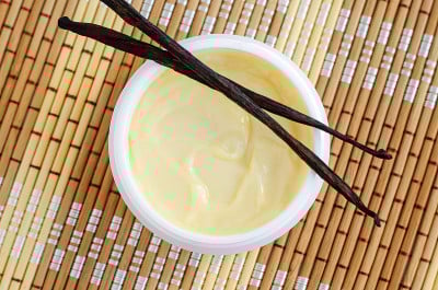 黄色香草面膜(香蕉霜，乳木果面膜，身体黄油)在小的白色罐子。天然护肤护发理念。俯视图，复制空间。