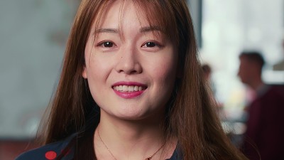 这是一幅20多岁年轻貌美的中国大学生在现代繁忙的办公室里对着镜头微笑的特写。