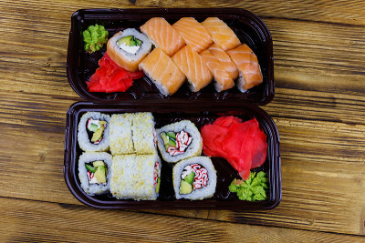 Set of sushi rolls in plastic boxes on wooden tabl