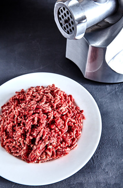 用绞肉机将生牛肉放在白盘子上