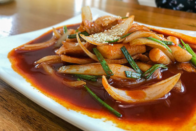 美味的韩国辣味鸡扒。木材背景上辛辣的竹木图案