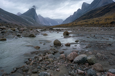 在一个阴天和雨天的偏远北极山谷的野生黄鼠狼河河床。加拿大巴芬岛阿克沙约克山口引人注目的北极景观。背景