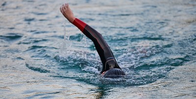 triathlon athlete swimming on lake in sunrise  wea