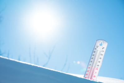 温度计放在雪地上，在寒冷的天气里蓝色的天空显示负温度。空气和环境温度低的气象条件。气候变化和全球变暖