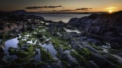 苏格兰西海岸风景优美的岩石海滩上的日落。