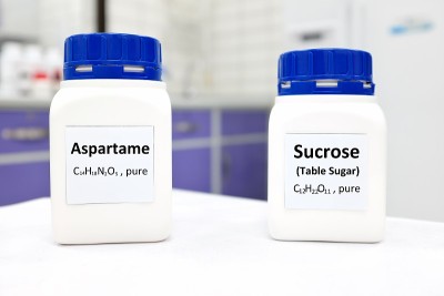 选择性集中一瓶纯阿斯巴甜人工甜味剂和蔗糖或蔗糖化学化合物的比较。白色的实验室背景和复制空间。