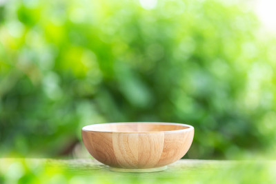 木桌上的空碗与绿色模糊的灯光背景