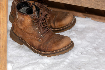 雪地里的长凳下面有一双旧登山靴