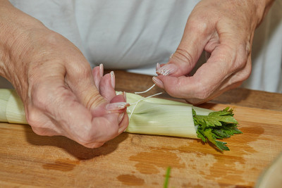 厨师用绳子把一束绿色蔬菜捆起来，盛在盘子里