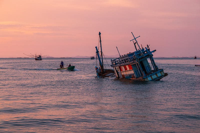 夕阳西下时在泰国湾海上的一艘旧船