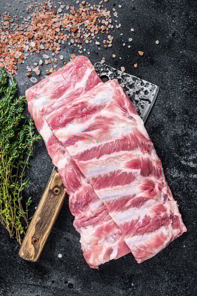 生的生猪肉排骨在屠夫切肉刀。黑色背景。俯视图