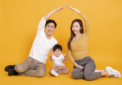 快乐年轻的家庭坐在地板上与家的概念
