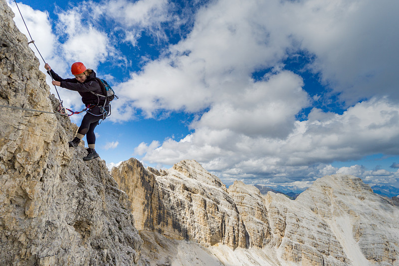 一位女性登山者在意大利白云岩的一个陡峭的Via Ferrata