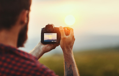 旅行摄影师。带着相机的旅行者在日落的大自然中