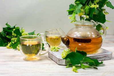 一把茶壶，两杯茶和一棵菩提树放在木桌上。治疗茶。