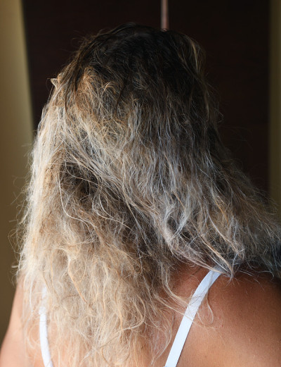金发梳理湿乱的头发。年轻女子洗完澡后梳理着乱糟糟的头发，特写镜头