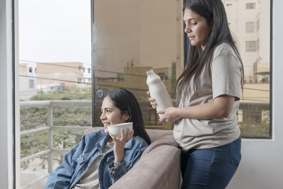 一位妇女在沙发上给一位妇女端上手工杏仁和椰奶