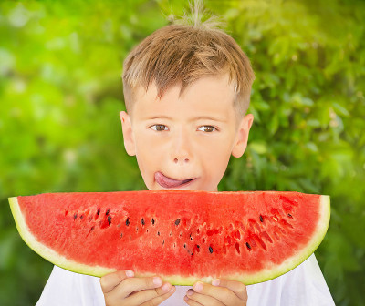 孩子拿着红色多汁的西瓜。