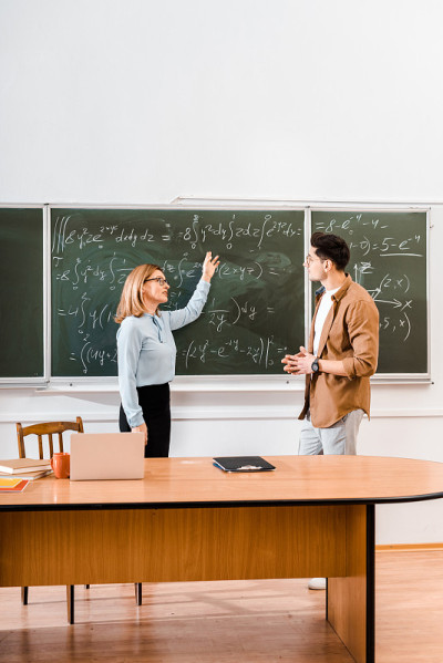 女老师在教室里指着方程式给学生看