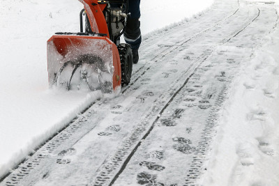 冬天，一名男子在变电站用吹雪机清除人行道上的积雪