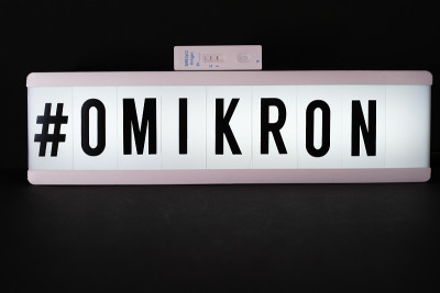 一张新冠抗原快速检测呈阳性的照片摆放在一块刻有#Omikron字样的光板旁边