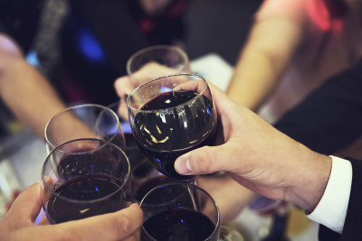 近距离的人们在餐厅的桌子上碰杯。在宴会上举杯祝酒。在晚宴上用饮料庆祝。男人们和女人们欢聚一堂。一个喝