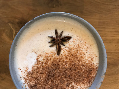玛沙拉茶拿铁传统温印度甜牛奶五香饮料，生姜，肉桂棒，新鲜香料混合有机注入健康养生饮料在乡村木桌