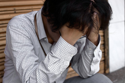 悲伤和压力的年轻亚洲男子与手在脸上遭受严重的抑郁症